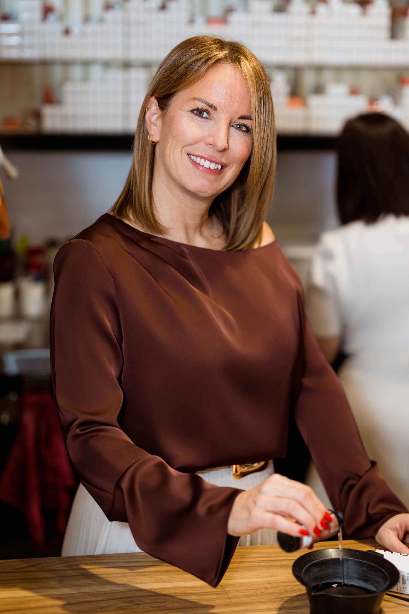 Femme en blouse marron à table.