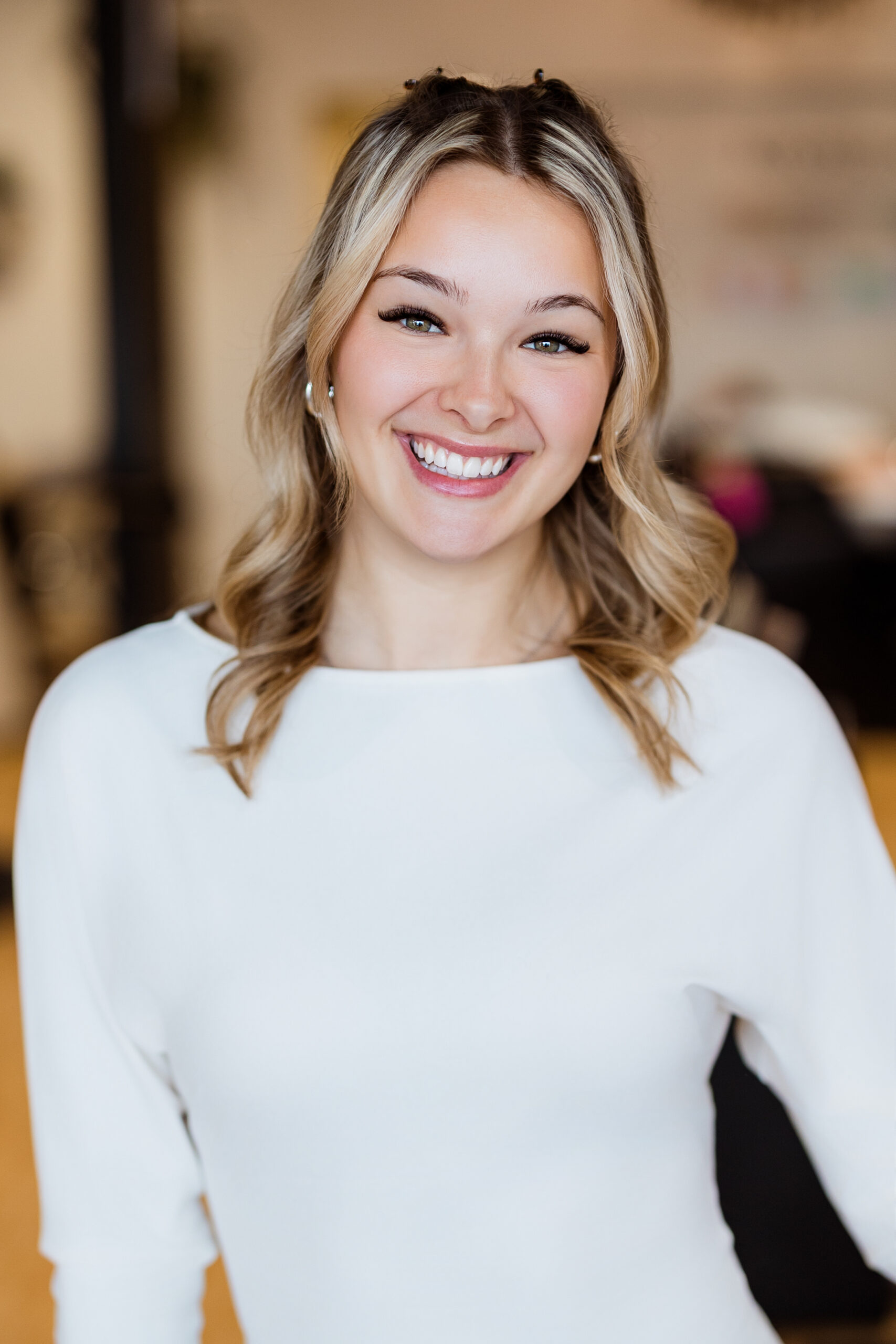 Femme en haut blanc, cheveux ondulés.
